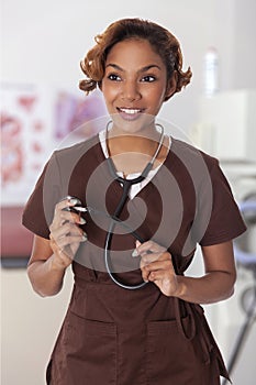 Woman in scrubs holds a stethoscope.