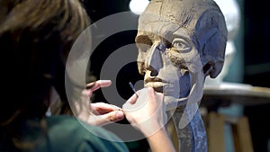 Woman sculptor at work on a sculpture of a human head.