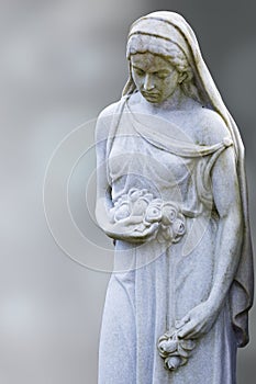 Woman sculpture at an old cemetery, blurred gray background