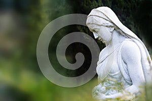 Woman sculpture with rose basket made of marble in a park or cem