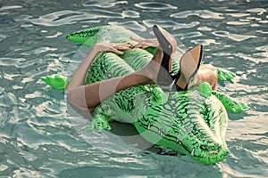Woman on sea with inflatable mattress. shoes from crocodile leather. female legs hold mattress in swimming pool. Fashion