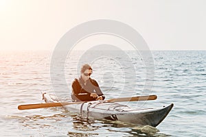 Woman sea kayak. Happy smiling woman in kayak on ocean, paddling with wooden oar. Calm sea water and horizon in