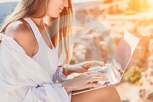 Woman sea laptop. Business woman in yellow hat freelancer with laptop working over blue sea beach. Girl relieves stress