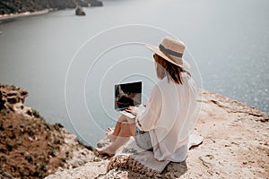 Woman sea laptop. Successful business woman working on laptop by the sea. Pretty lady typing on computer at summer day