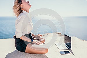 Woman sea laptop yoga. Business woman freelancer in yoga pose working over blue sea beach at laptop and meditates. Girl