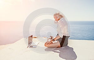 Woman sea laptop yoga. Business woman freelancer in yoga pose working over blue sea beach at laptop and meditates. Girl