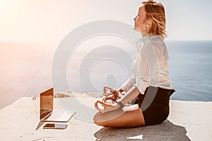 Woman sea laptop yoga. Business woman freelancer in yoga pose working over blue sea beach at laptop and meditates. Girl