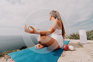 Woman sea pilates. Sporty happy middle-aged woman practices pilates on a beach near the sea, promoting a healthy