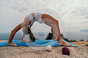 Woman sea pilates. Sporty happy middle-aged woman practices pilates on a beach near the sea, promoting a healthy