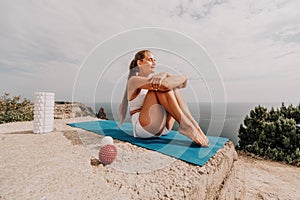 Woman sea pilates. Sporty happy middle-aged woman practices pilates on a beach near the sea, promoting a healthy