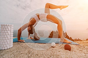 Woman sea pilates. Sporty happy middle-aged woman practices pilates on a beach near the sea, promoting a healthy