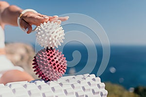 Woman sea pilates. Sporty happy middle aged woman practicing fitness on yoga mat with massage balls and roller near sea
