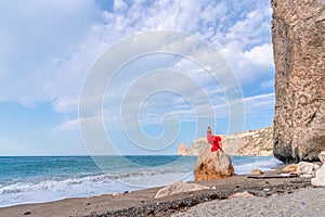 woman sea red dress. Woman with long hair on a sunny seashore in a red flowing dress, back view, silk fabric waving in