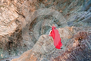 woman sea red dress. Woman with long hair on a sunny seashore in a red flowing dress, back view, silk fabric waving in