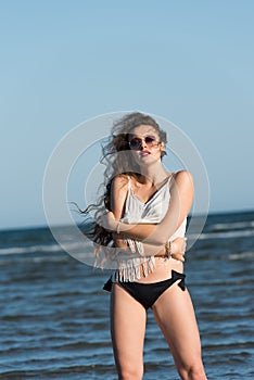 Woman in sea water wear bikini, sunglasses and white shirt