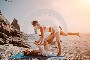 Woman sea yoga. Two happy women practicing yoga on the beach with ocean and rock mountains. Motivation and inspirational