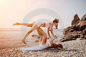 Woman sea yoga. Two happy women practicing yoga on the beach with ocean and rock mountains. Motivation and inspirational