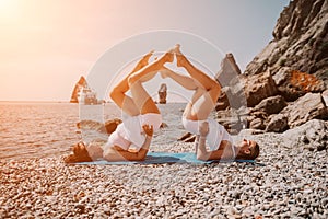 Woman sea yoga. Two happy women practicing yoga on the beach with ocean and rock mountains. Motivation and inspirational