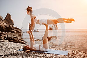 Woman sea yoga. Two happy women practicing yoga on the beach with ocean and rock mountains. Motivation and inspirational