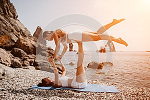 Woman sea yoga. Two happy women practicing yoga on the beach with ocean and rock mountains. Motivation and inspirational