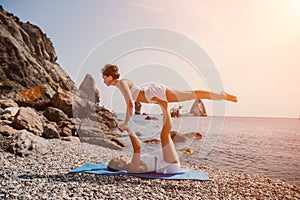 Woman sea yoga. Two happy women practicing yoga on the beach with ocean and rock mountains. Motivation and inspirational