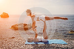 Woman sea yoga. Two happy women practicing yoga on the beach with ocean and rock mountains. Motivation and inspirational