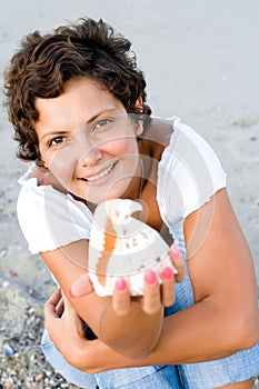 Woman on seacoast with a cockleshell in hands