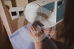 A woman seamstress sews on a sewing machine at home.