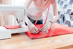 Woman seamstress working making pattern on red fabric