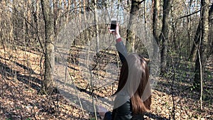 Woman searches for phone signal in the woods