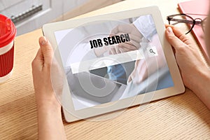 Woman searching job on tablet at wooden table