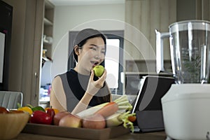 Woman searching online recipe on digital tablet and preparing ingredients for making vegetables detox smoothie.