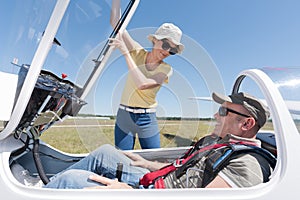 Woman securing cockpit over man in sailplane