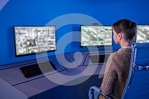 Woman security guard looking at modern cctv camera monitors