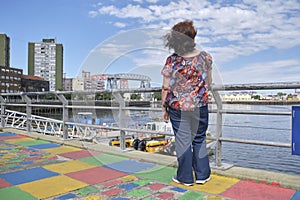 Woman seen from the back looking towards the Riachuelo, in La Boca, Buenos Aires photo