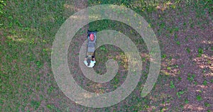 A woman is seen mowing the green lawn in her backyard with a lawn mower located close to her home