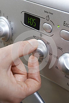 Woman Selecting Cooler Temperature On Washing Machine To Save En