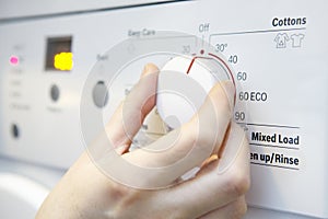 Woman Selecting Cooler Temperature On Washing Machine To Save En photo