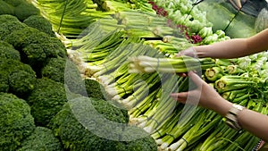 Woman selecting green onion in grocery store