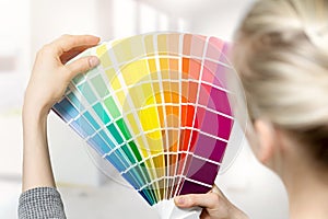 Woman selecting home interior paint color from swatch catalog