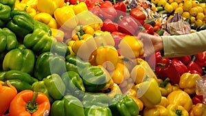 Woman selecting yellow peppers in grocery store