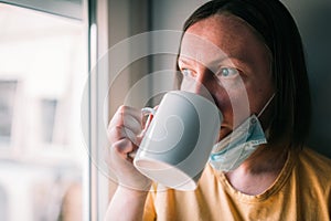 Woman in self-isolation during virus outbreak drinking coffee