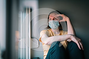 Woman in self-isolation during virus outbreak looking through window