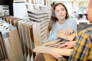 Woman seller advises a buyer in choosing a laminate in hardware store photo