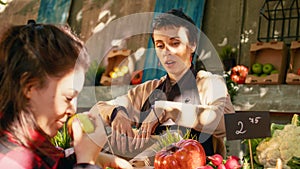 Woman seller helping client pick various organic fruits and veggies