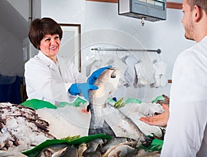 Woman selling fish to male customer