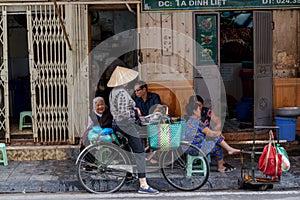 Woman is selling fruits from bicycle on the street.