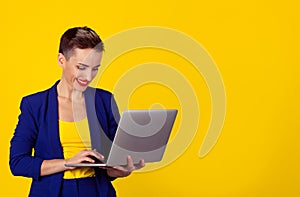 Woman sending emails standing with her computer balanced on her hand