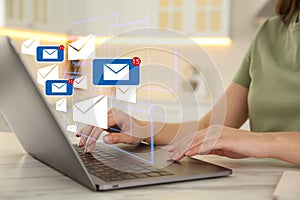 Woman sending emails at table in kitchen