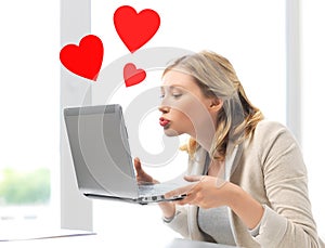 Woman sending kisses with laptop computer